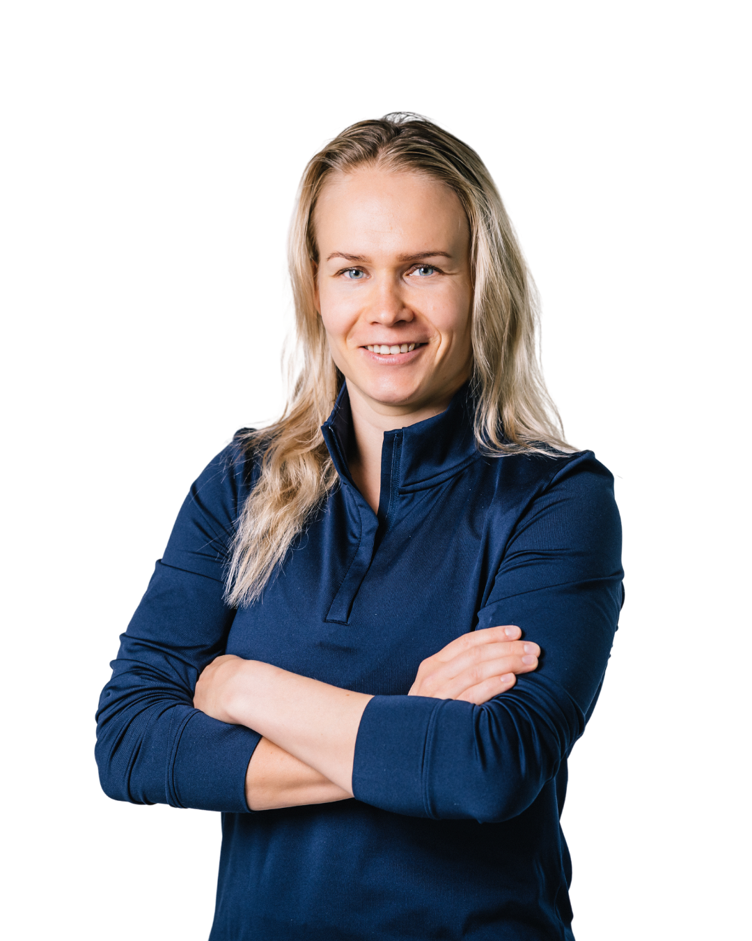 A blonde woman with a friendly smile stands with her arms crossed against a white background.