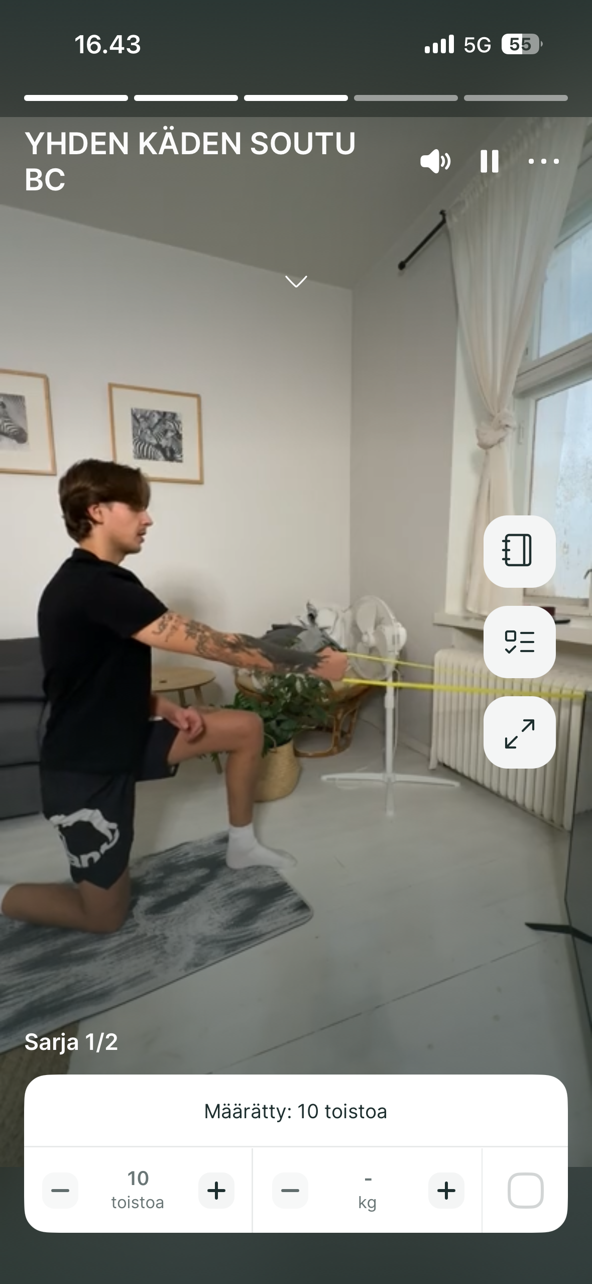 A person in a half-kneeling position performs a single-arm row exercise using a resistance band in a home setting.