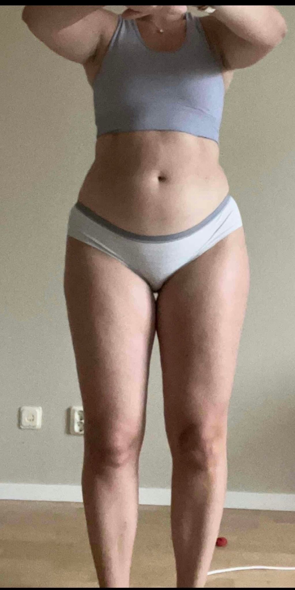 A person standing in athletic wear for a fitness progress check.