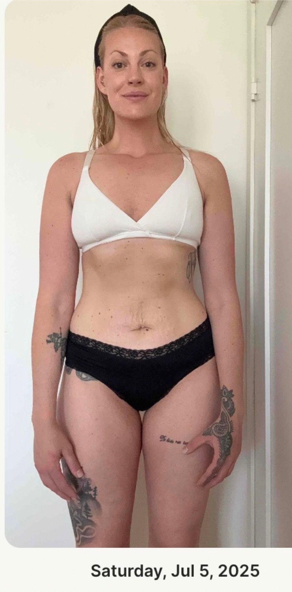 A woman stands facing forward in athletic undergarments for a fitness progress check.