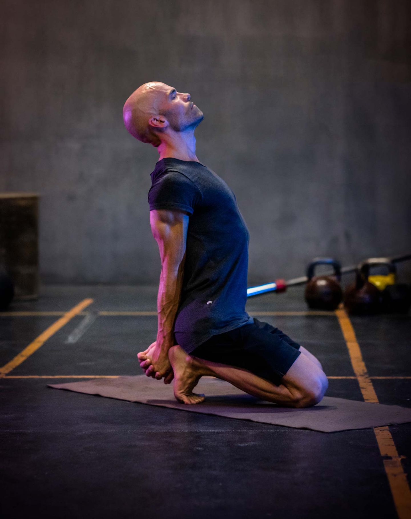 Tränare utför yoga position på knä med bakåtböjning.