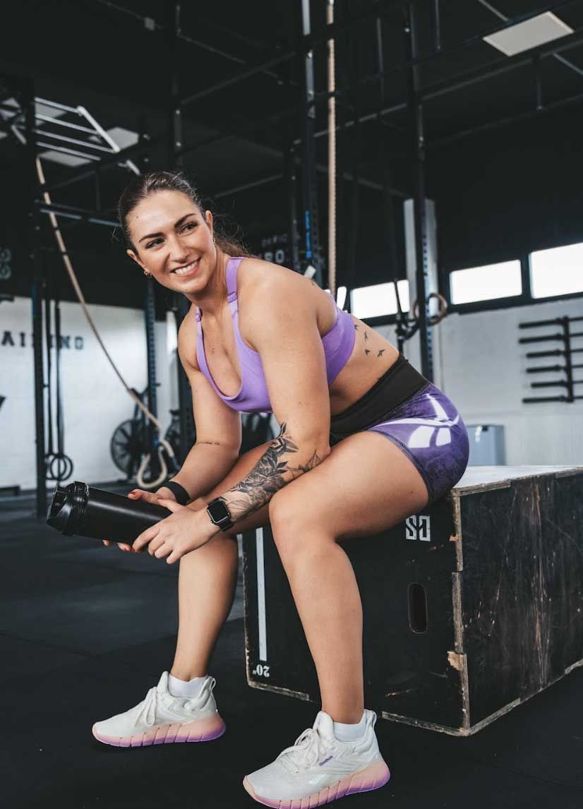 Die Trainerin posiert in Fitnesskleidung.