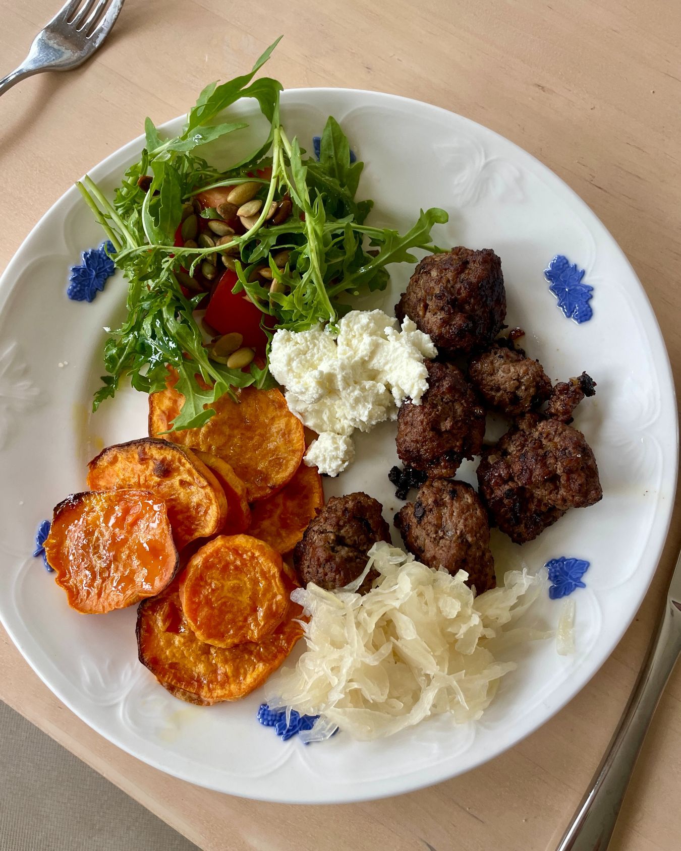 Tallrik med köttbullar, sötpotatis, ruccola och fetaost.