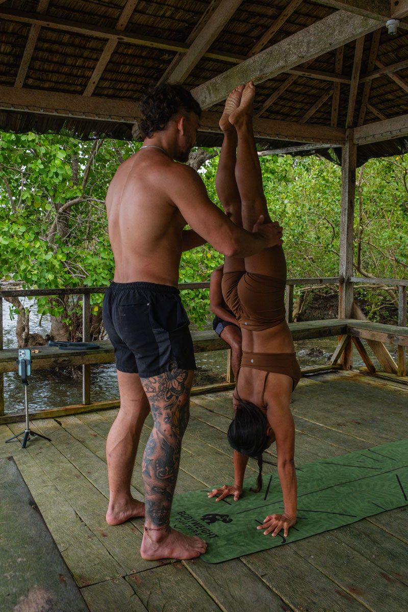 The coach is helping the lead to do the yoga.