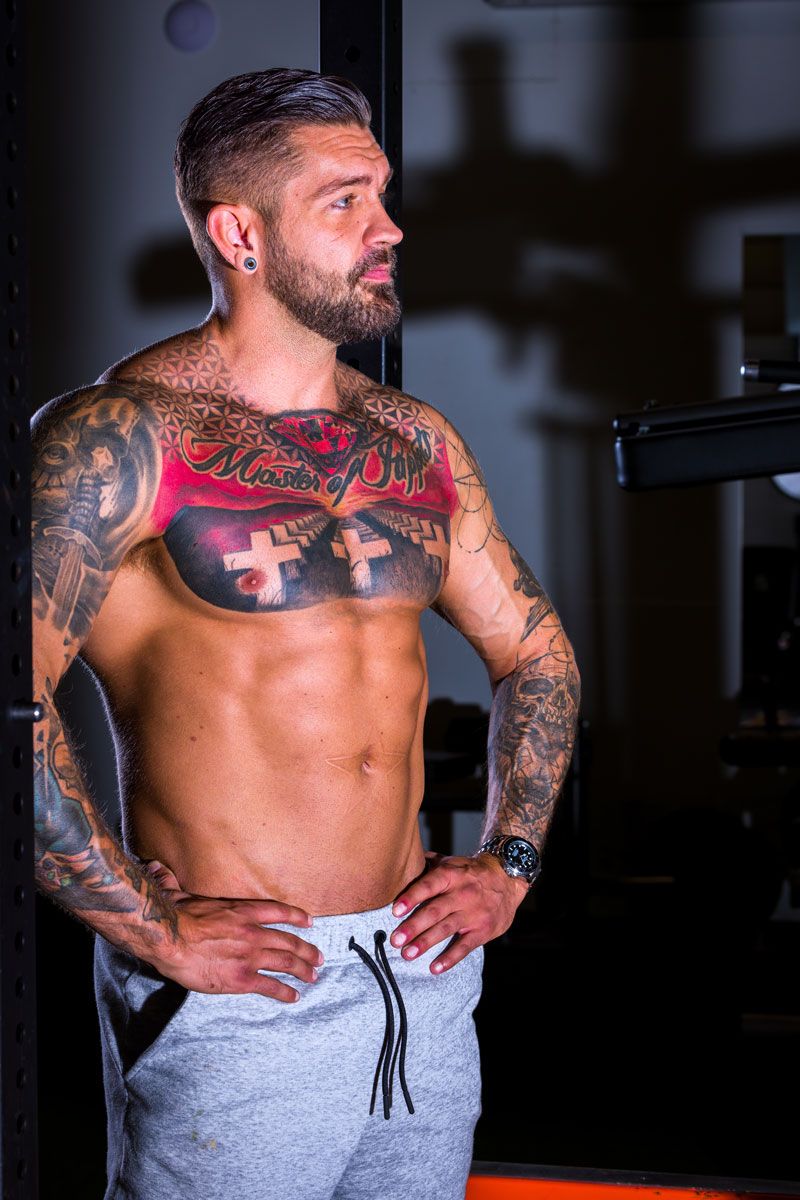 Coach is posing topless showing his tattoos.