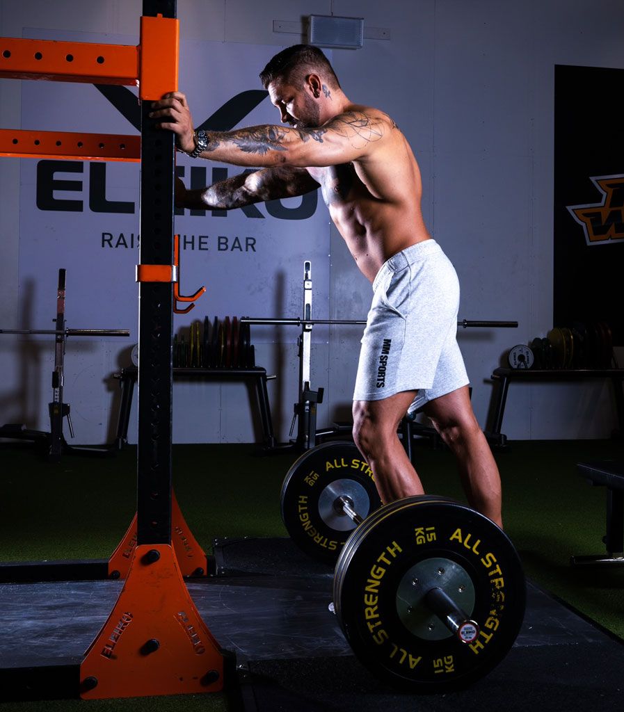 Coach is exercising in the gym, shirtless.