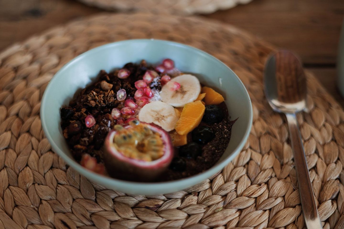 Ontbijtbowl met granola, banaan, mango, blauwe bessen, granaatappel en passievrucht